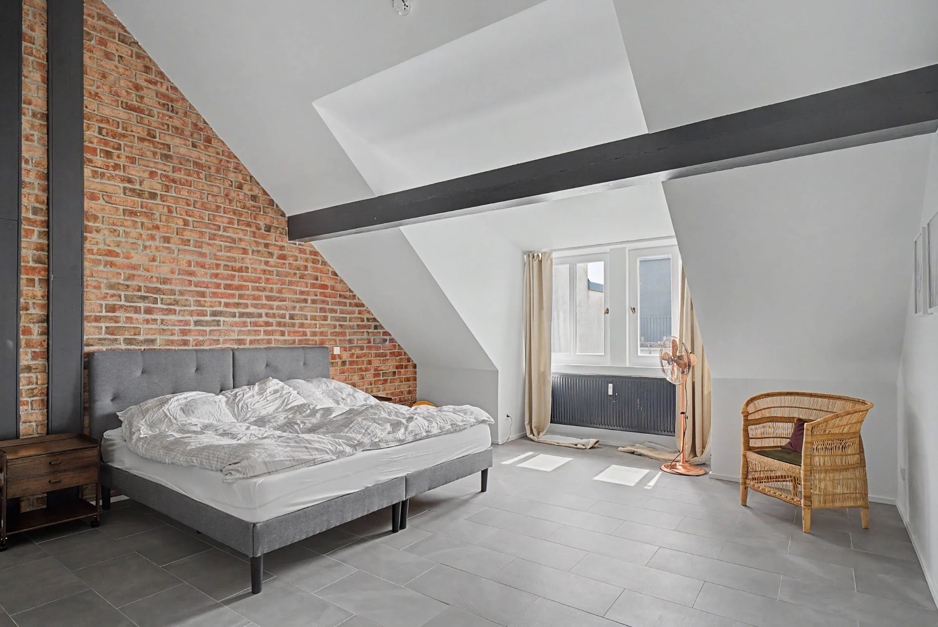 Schlafzimmer mit gepolstertem Bett und Backsteinwand im Dachgeschoss-Loft in Berlin-Kreuzberg — Interieurfotografie